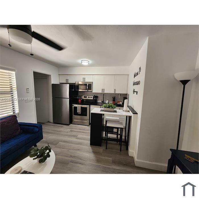 A bedroom features a black metal bed frame, a gear-themed wall clock, and industrial shelving — 2032 NE 26th St # 3, Wilton Manors FL 33305, WILTON MANORS, FL