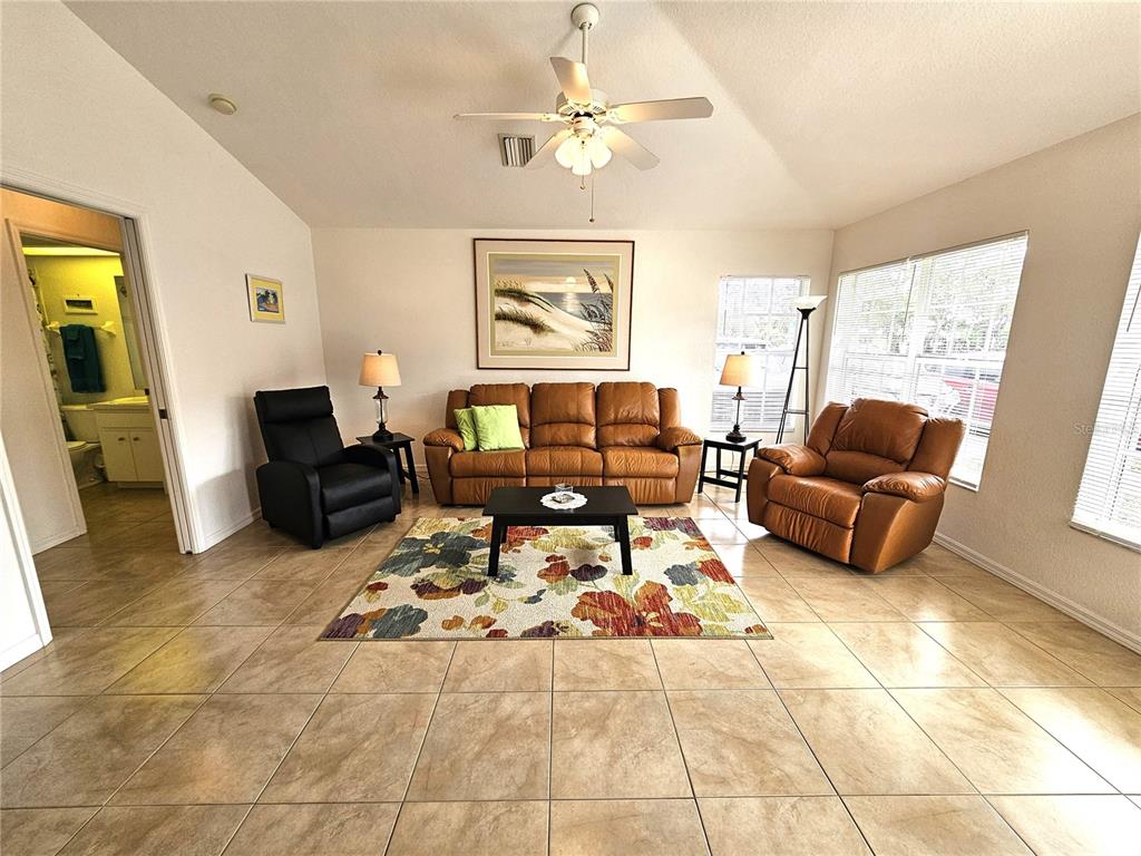 A living room features tile flooring, a brown leather sofa, and a ceiling fan — 70 N MCCALL ROAD, ENGLEWOOD, FL