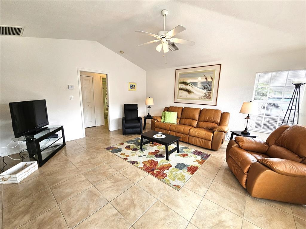 A living room features tile floors, a vaulted ceiling, and tan leather furniture — 70 N MCCALL ROAD, ENGLEWOOD, FL