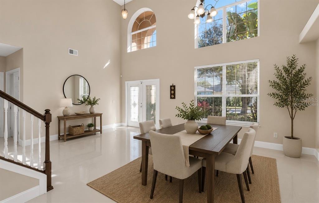 A dining room with high ceilings, a wooden table, and large windows overlooking the outdoors — 2508 BROSS DRIVE, ST CLOUD, FL