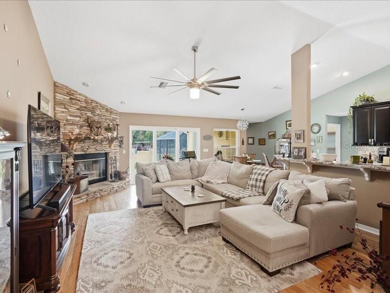 A living room features a stone fireplace, a large sectional sofa, and a ceiling fan — 19950 SW 5TH PLACE, DUNNELLON, FL