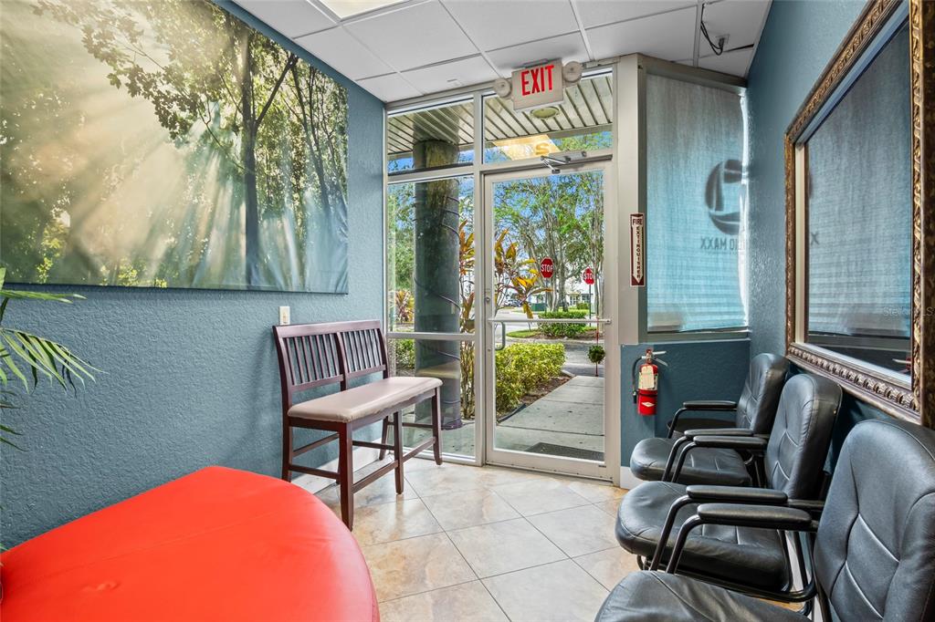 A waiting area features a red bench, black chairs, a forest wall mural, and glass doors — 7901 KINGSPOINTE PARKWAY UNIT 2, ORLANDO, FL