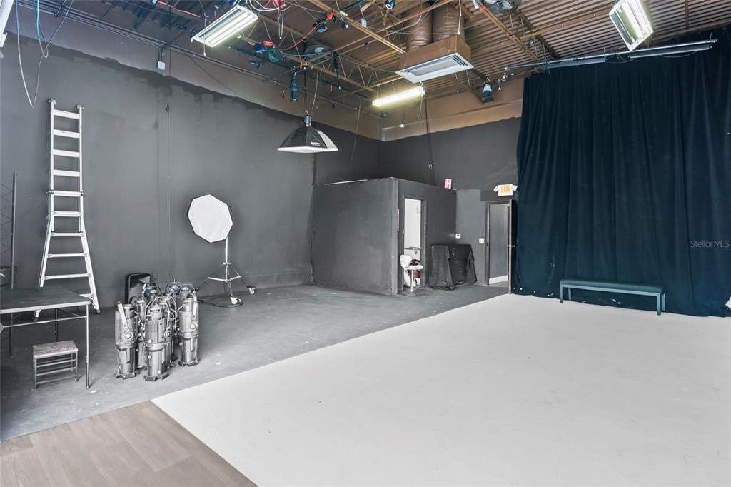 A professional photography studio features black walls, a white floor, lighting equipment, and a ladder — 7901 KINGSPOINTE PARKWAY UNIT 2, ORLANDO, FL