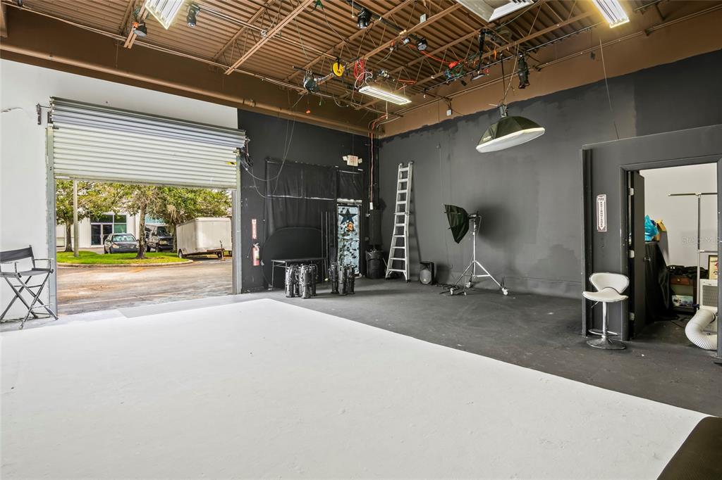 A studio space with a white floor, black walls, lighting equipment, and an open garage door — 7901 KINGSPOINTE PARKWAY UNIT 2, ORLANDO, FL