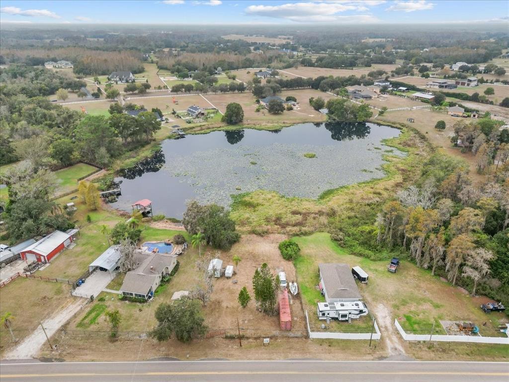 An aerial view shows two houses with a pool and RV near a large pond — 17524 BOY SCOUT ROAD, ODESSA, FL