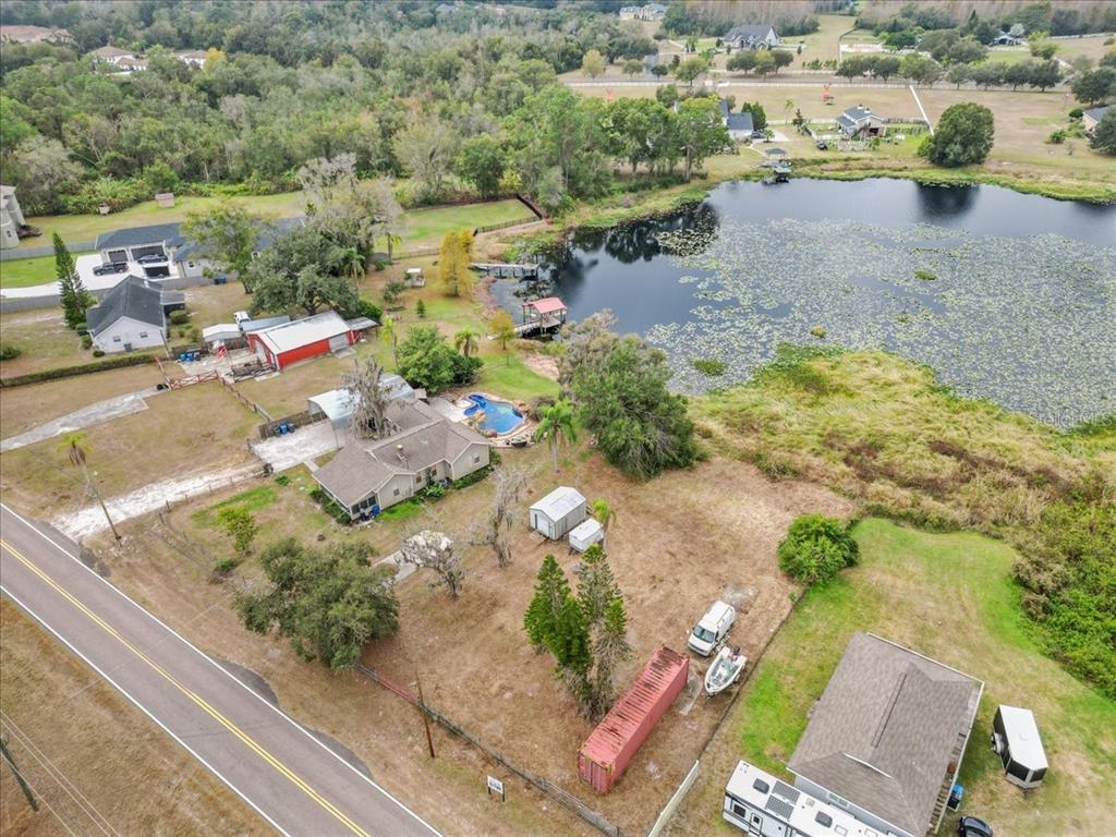An aerial view shows a rural property with a house, pool, outbuildings, and a pond — 17524 BOY SCOUT ROAD, ODESSA, FL