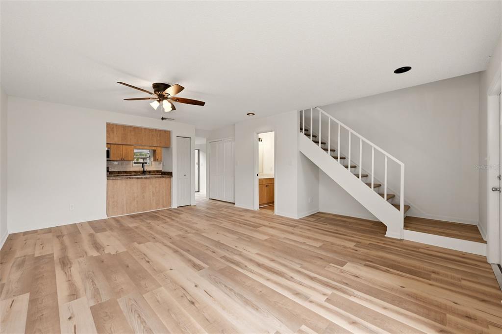 A living room with light wood flooring, a ceiling fan, stairs, and sliding glass doors — 7906 TANGERINE DRIVE, TAMPA, FL