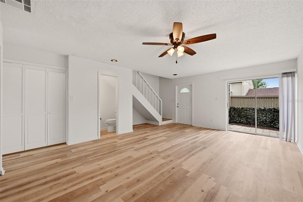 A living room with light wood flooring, a ceiling fan, and an open kitchen pass-through — 7906 TANGERINE DRIVE, TAMPA, FL