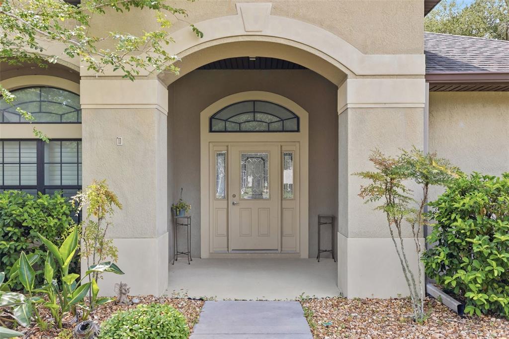 The exterior entrance features a tan stucco facade, an arched entryway, and a front door — 27127 STONEY BROOK DRIVE, LEESBURG, FL
