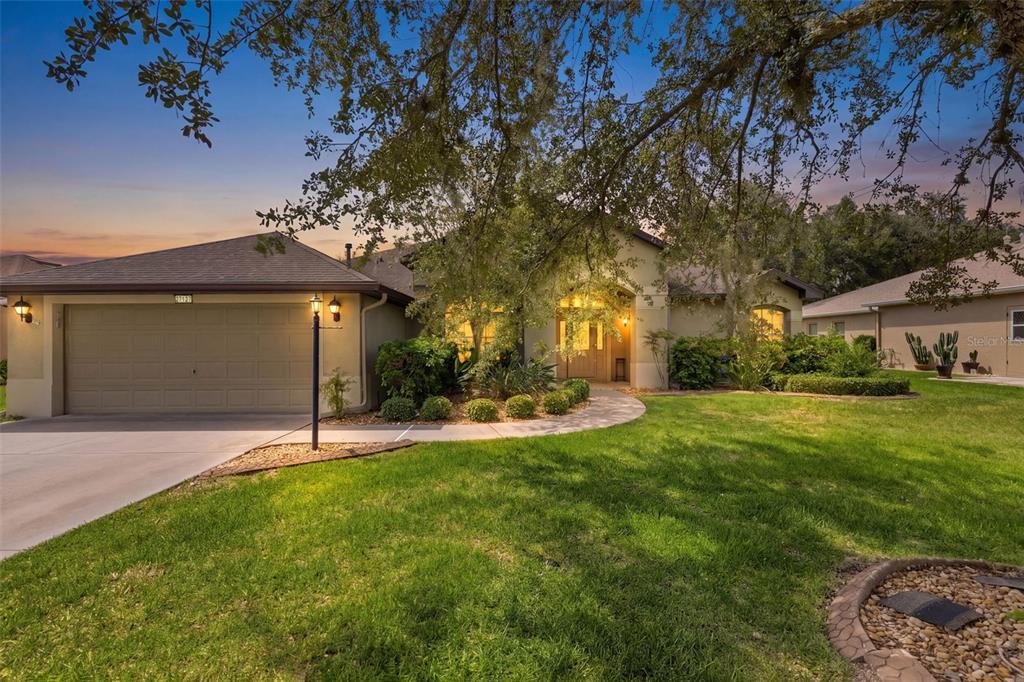 A single-story house with a two-car garage, a paved walkway, and a large front lawn — 27127 STONEY BROOK DRIVE, LEESBURG, FL