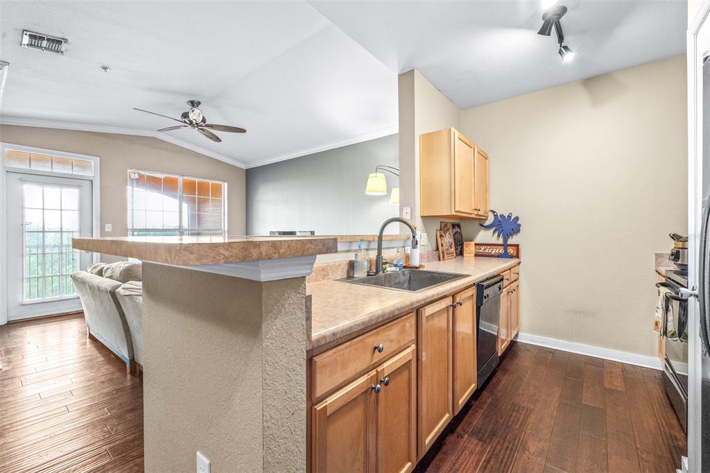 A kitchen with light wood cabinets, laminate countertops, and a breakfast bar overlooks a living area — 5000 CULBREATH KEY WAY UNIT 1-309, TAMPA, FL