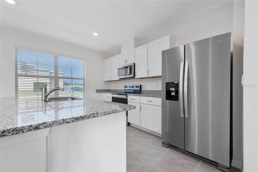 A kitchen features white cabinets, granite countertops, stainless steel appliances, and a large island — 1627 BITTEROOT STREET, KISSIMMEE, FL