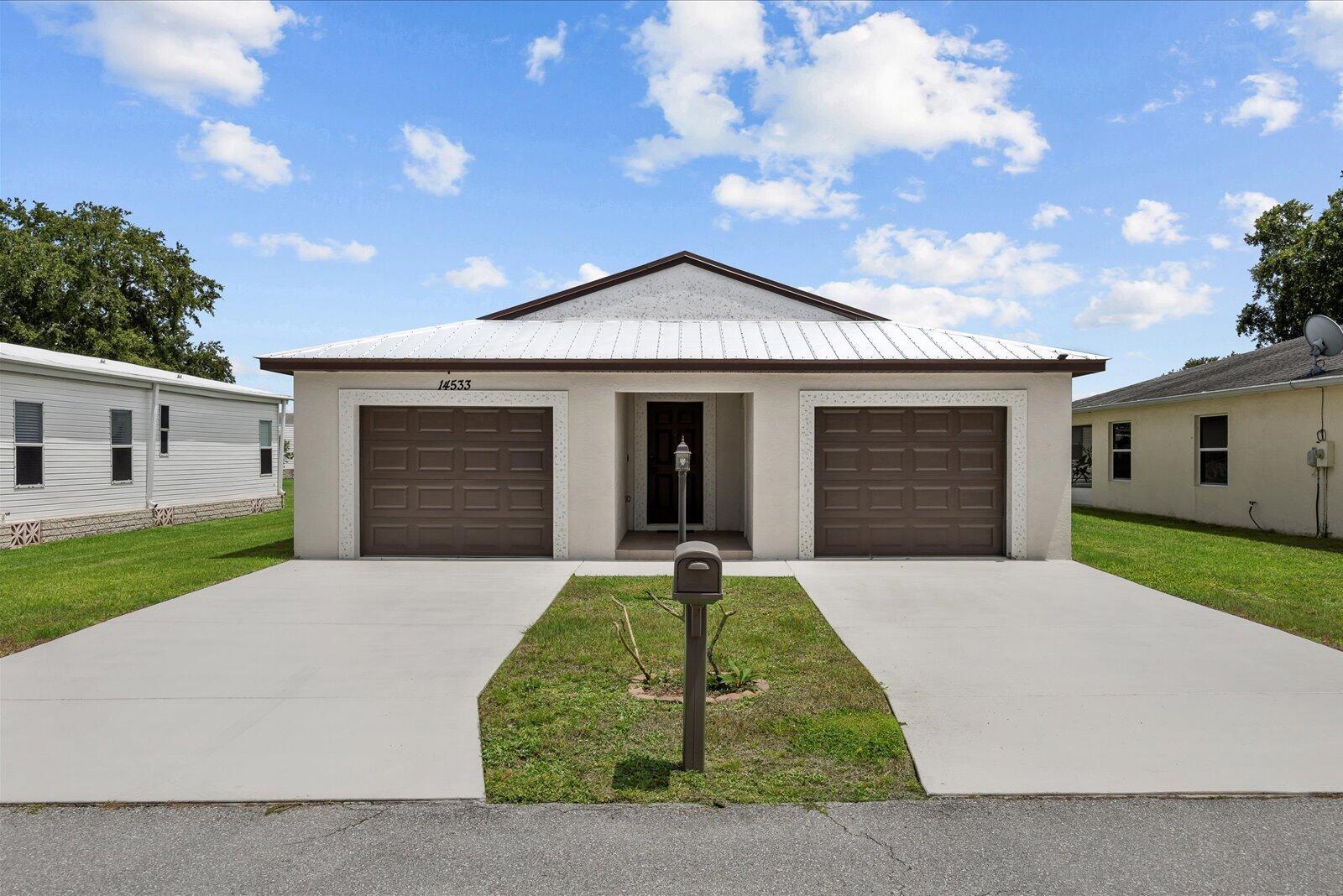 A single-story house with a metal roof, two garage doors, and a concrete driveway — 14533 Dulce Avenue, Fort Pierce FL 34951, FORT PIERCE, FL