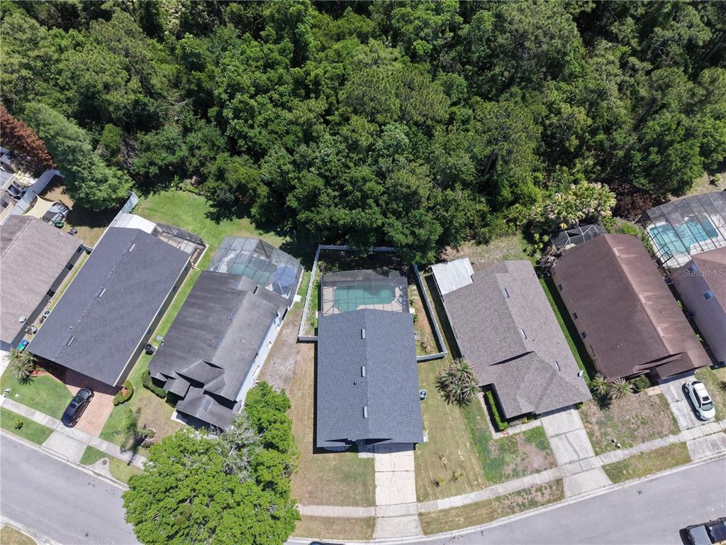 An aerial view shows a row of suburban houses with swimming pools and wooded backyards — 3103 BELLINGHAM DRIVE, ORLANDO, FL