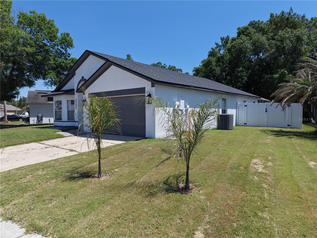 A white single-story house with a gray roof, garage, and two small palm trees — 3103 BELLINGHAM DRIVE, ORLANDO, FL