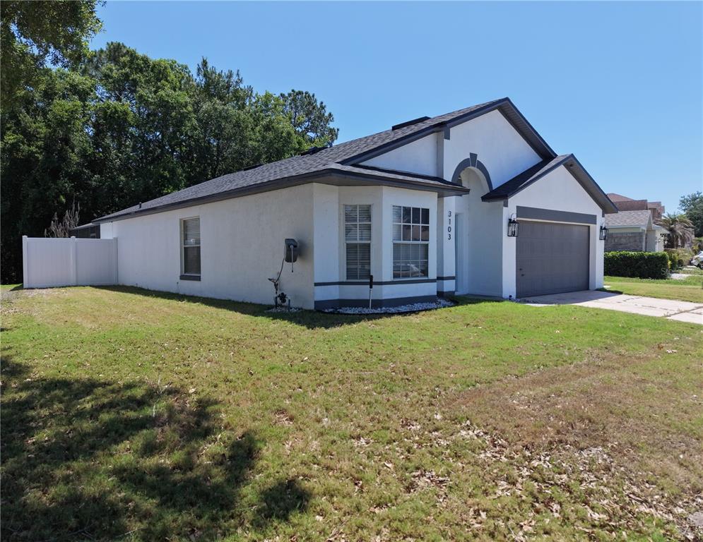 A single-story house with a white stucco exterior, dark trim, and an attached garage — 3103 BELLINGHAM DRIVE, ORLANDO, FL