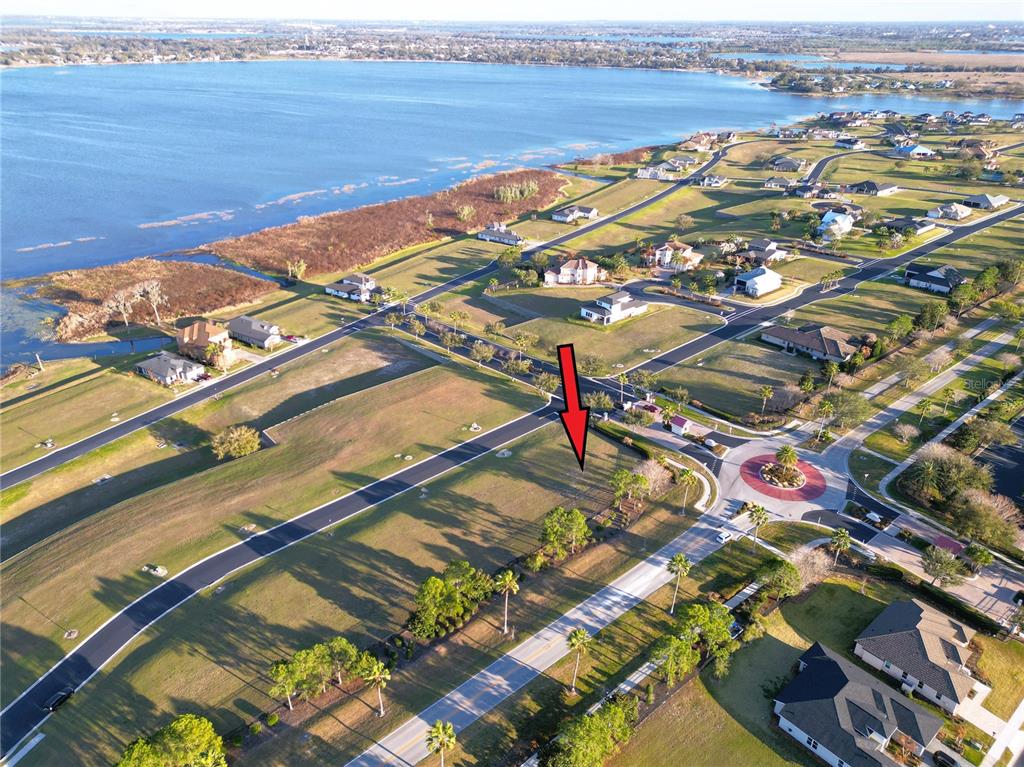 An aerial view shows a vacant residential lot marked by a red arrow near water — 508 BONAMIA AVENUE, LAKE ALFRED, FL