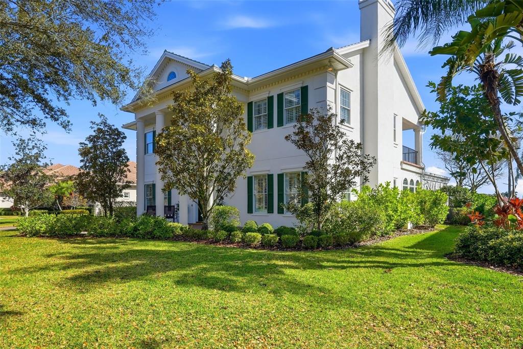 A two-story white house with green shutters and a front porch stands on a lawn — 7917 BAYOU CLUB BOULEVARD, SEMINOLE, FL