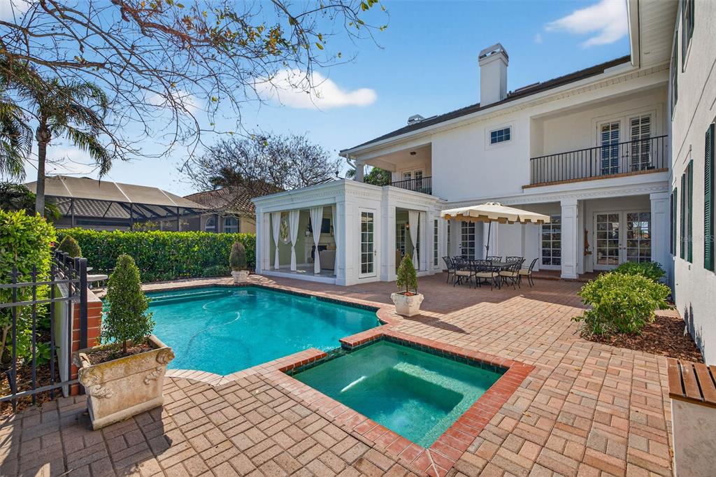 A backyard features a swimming pool, a spa, and a patio next to a house — 7917 BAYOU CLUB BOULEVARD, SEMINOLE, FL