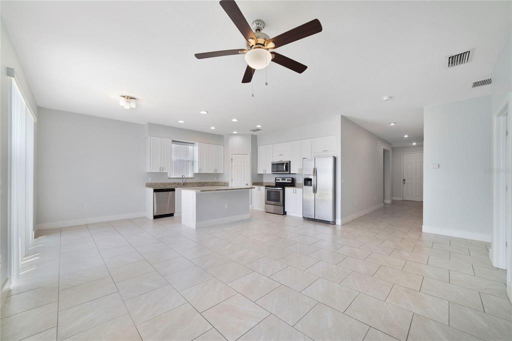 A kitchen with white cabinets, stainless steel appliances, and tile flooring in an open room — 128 WILLOW DRIVE, POINCIANA, FL