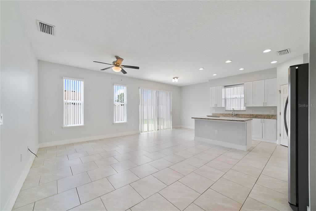 An open-concept living area with tile flooring, a kitchen island, and white cabinetry — 128 WILLOW DRIVE, POINCIANA, FL