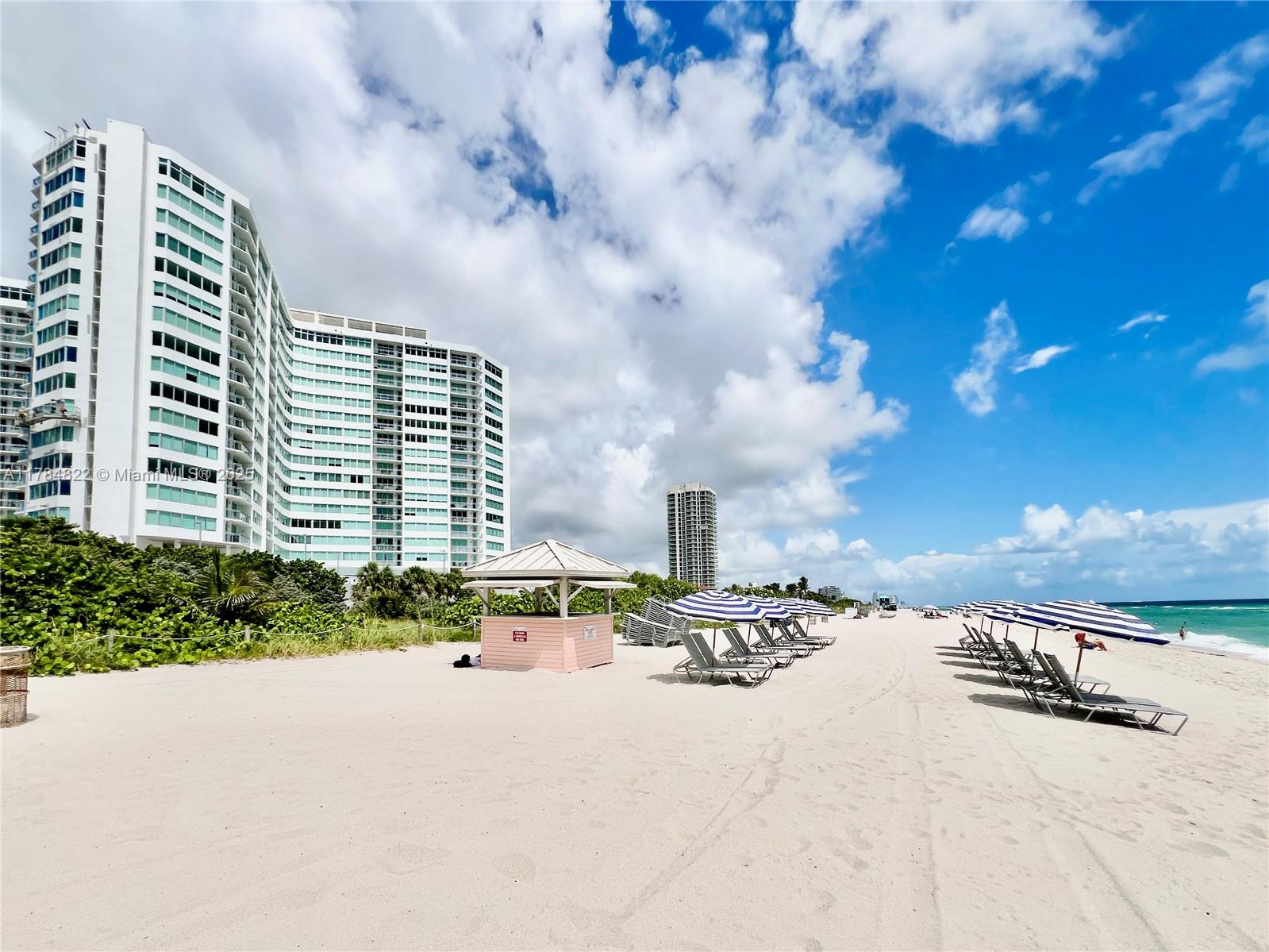 A sandy beach features rows of lounge chairs, umbrellas, a small pink hut, and high-rise buildings — 7135 Collins Ave # 621, Miami Beach FL 33141, MIAMI BEACH, FL