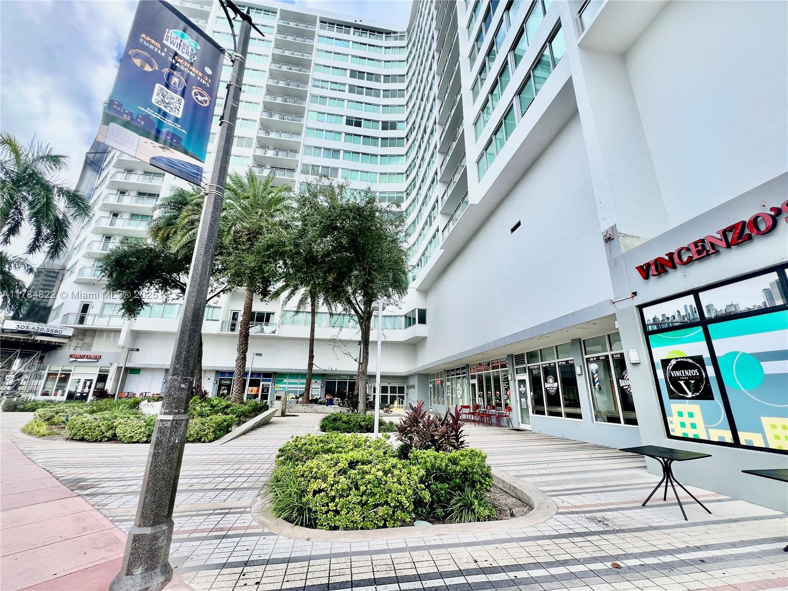A multi-story apartment building features ground-floor retail shops and a landscaped pedestrian plaza — 7135 Collins Ave # 621, Miami Beach FL 33141, MIAMI BEACH, FL