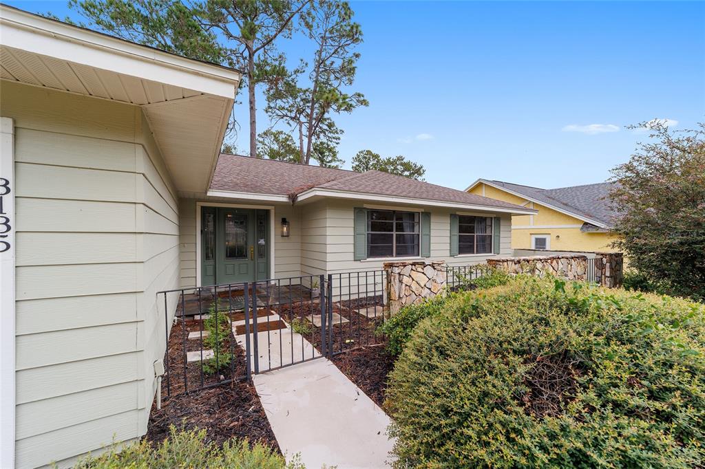 A single-story house with light green siding, a gated front walkway, and stone accents — 8185 NW 48TH LANE, OCALA, FL