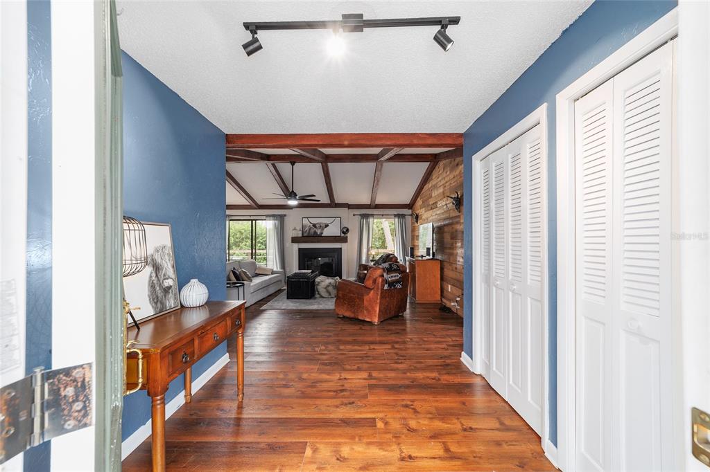 An entryway with blue walls and wood floors leads into a living room with beams — 8185 NW 48TH LANE, OCALA, FL