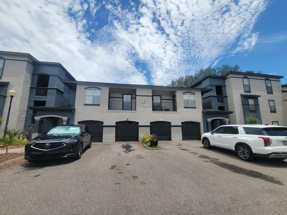 A two-story townhouse exterior features four garage doors, two balconies, and two parked cars — 8413 LUCUYA WAY UNIT 306, TEMPLE TERRACE, FL