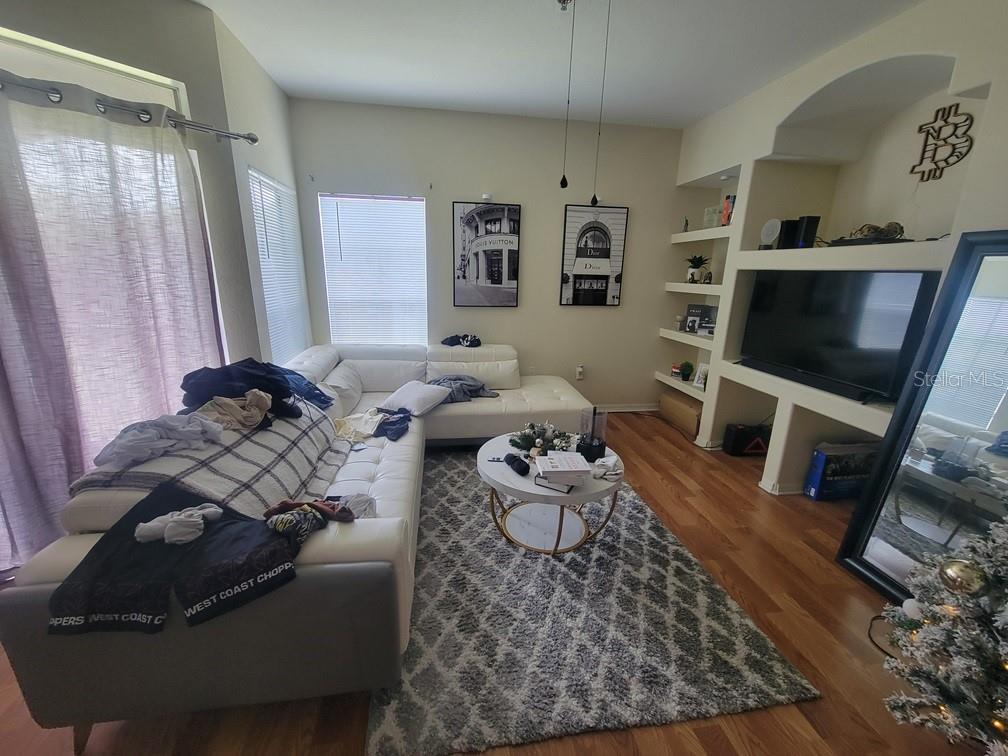 A living room features a white sectional sofa, a round coffee table, and built-in shelving — 8413 LUCUYA WAY UNIT 306, TEMPLE TERRACE, FL