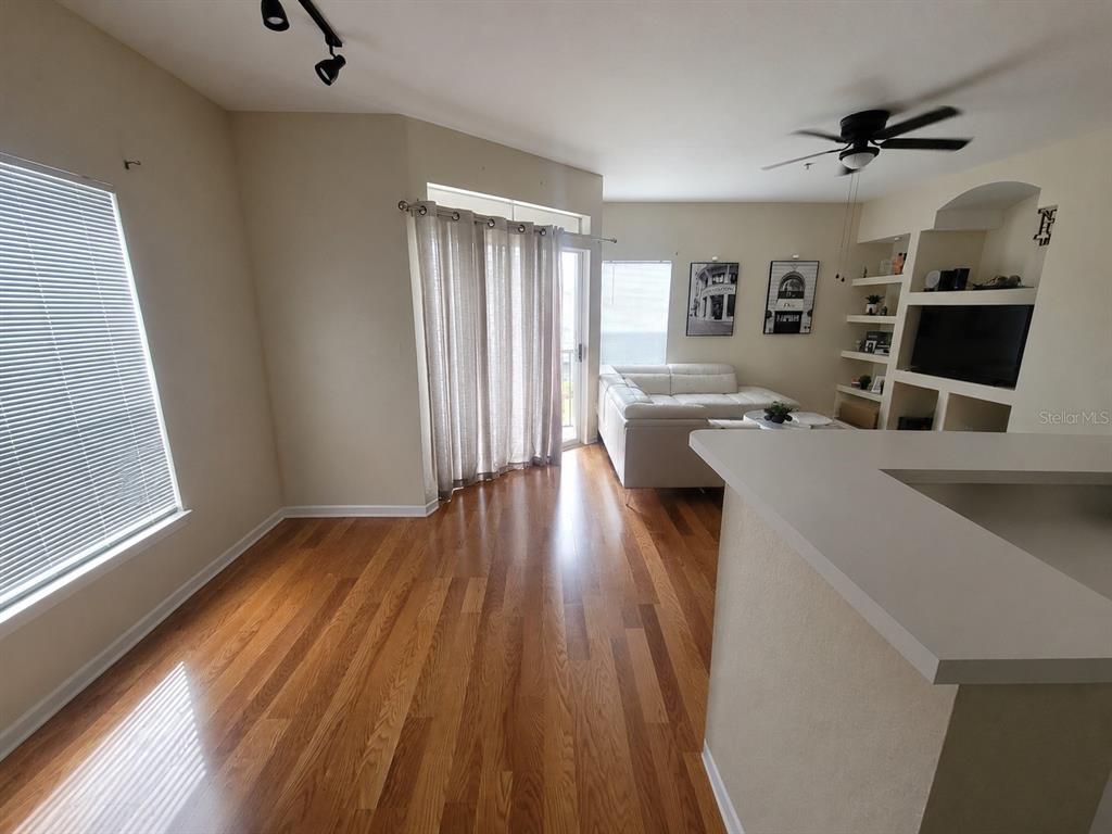 A living room with hardwood floors, a white sofa, and built-in shelving — 8413 LUCUYA WAY UNIT 306, TEMPLE TERRACE, FL