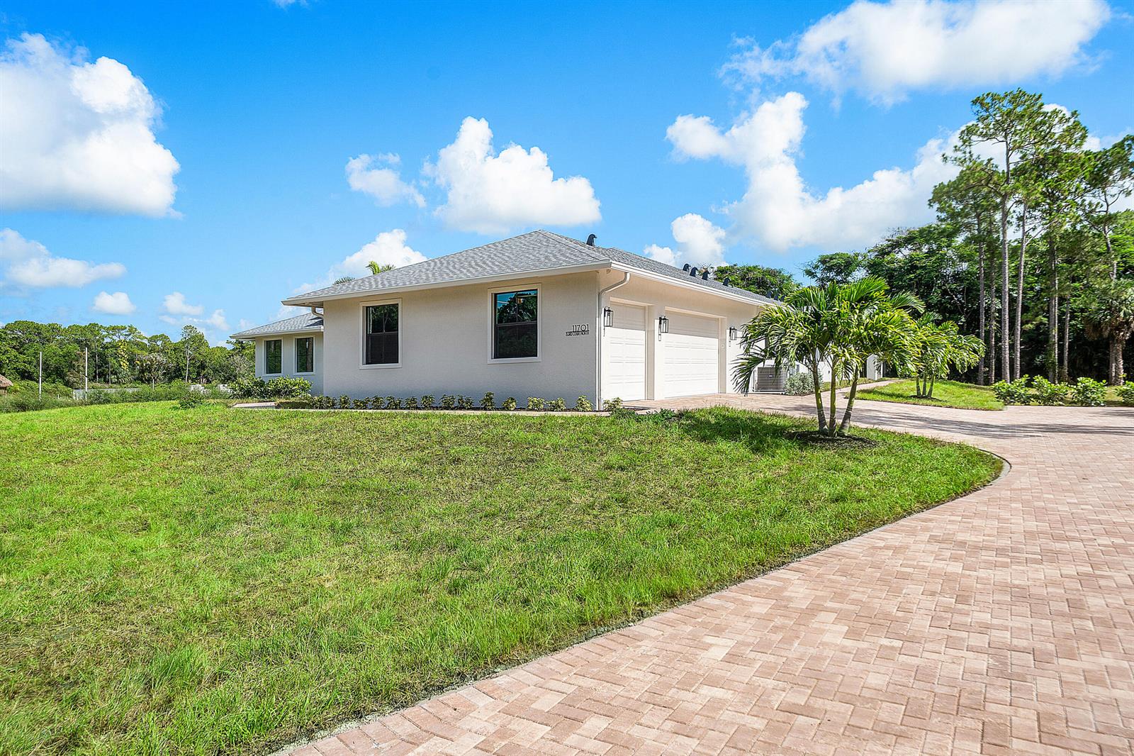 A single-story house with a paved driveway, two-car garage, and a large grassy lawn — 11701 153rd Court N, Jupiter FL 33478, JUPITER, FL