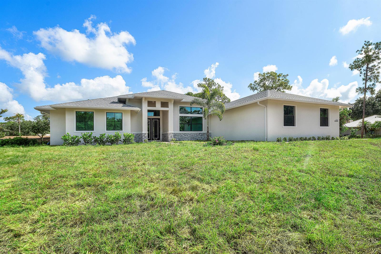 A single-story house with a light-colored exterior, stone accents, and a large front lawn — 11701 153rd Court N, Jupiter FL 33478, JUPITER, FL