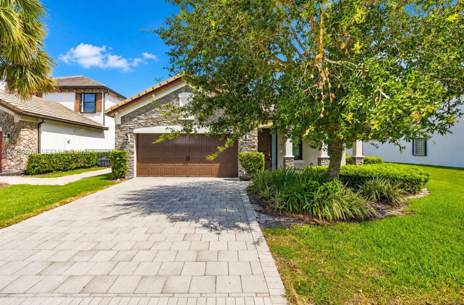 A single-story house with a stone facade, a brown garage door, and a paved driveway — 5836 Sandbirch Way, Lake Worth FL 33463, LAKE WORTH, FL