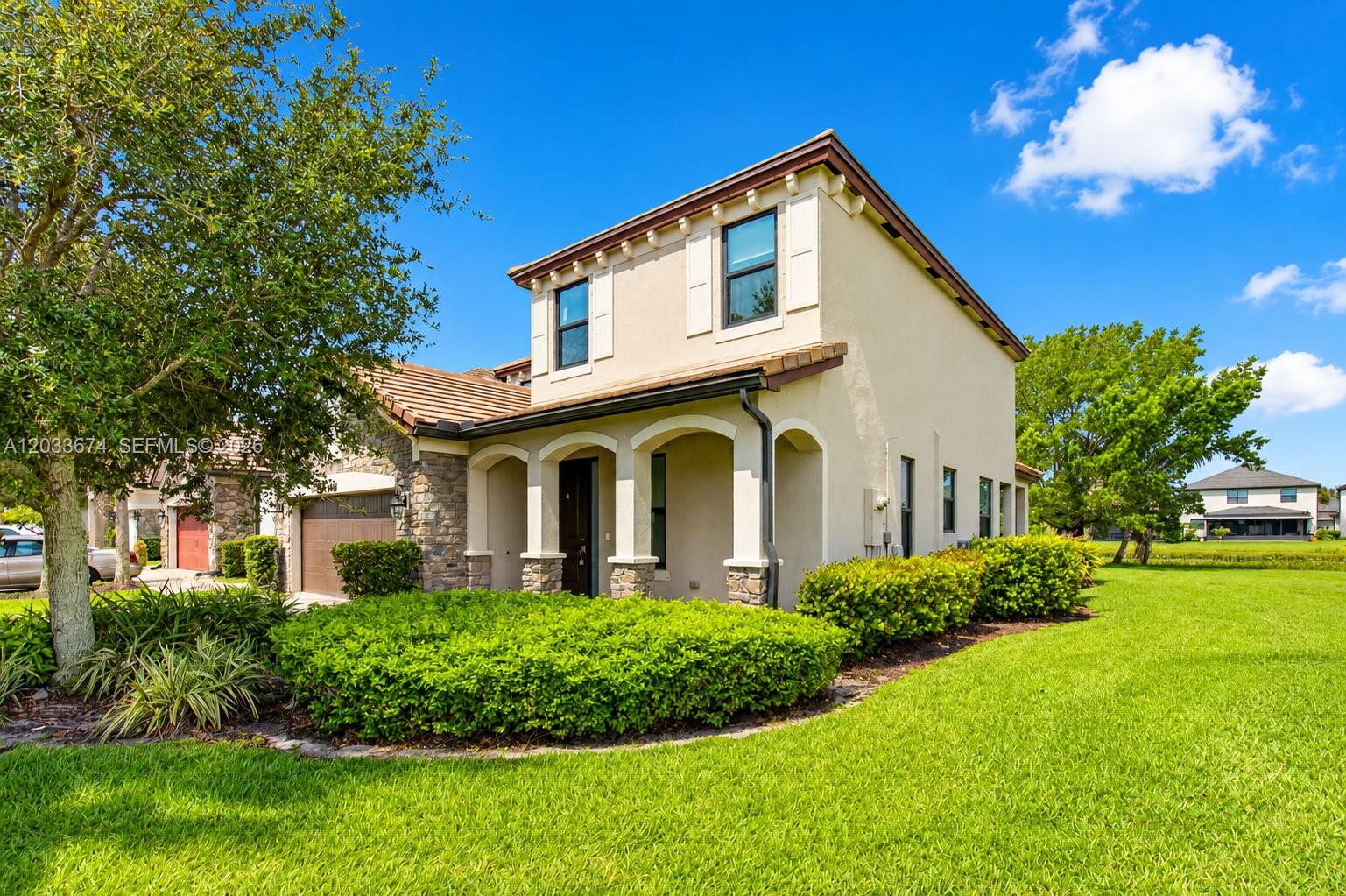 A two-story stucco house with stone accents and a covered entryway sits on a lawn — 5836 Sandbirch Way, Lake Worth FL 33463, LAKE WORTH, FL