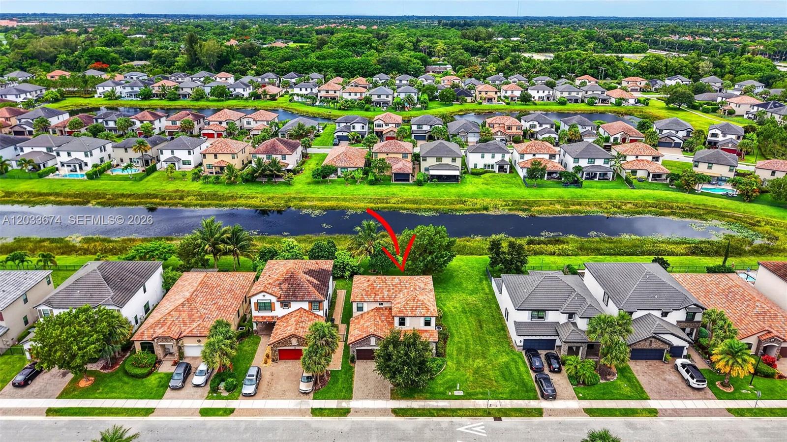 An aerial view shows a suburban neighborhood with houses, a canal, and a red arrow — 5836 Sandbirch Way, Lake Worth FL 33463, LAKE WORTH, FL