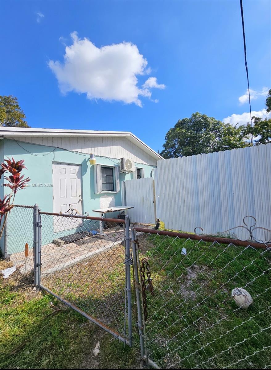 A light blue house exterior features a white door, a window, and a chain-link fence — 1760 NW 135th St, Miami FL 33167, MIAMI, FL