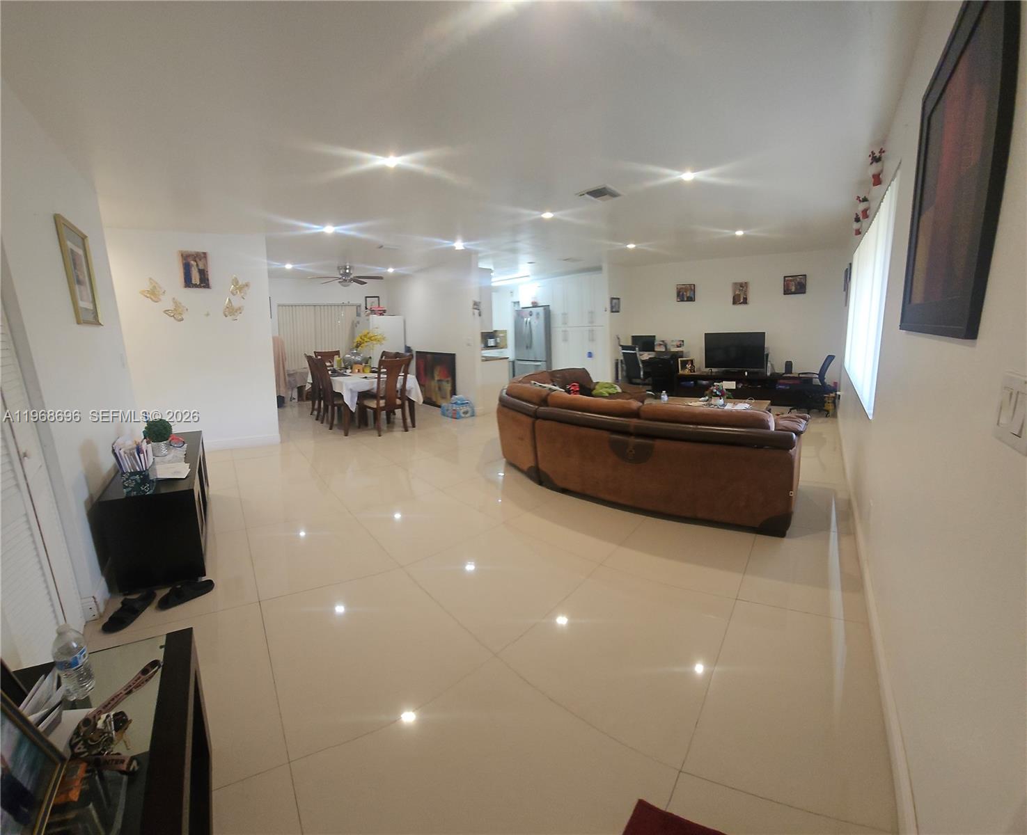 An open-concept living and dining area features large light-colored floor tiles and recessed lighting — 1760 NW 135th St, Miami FL 33167, MIAMI, FL