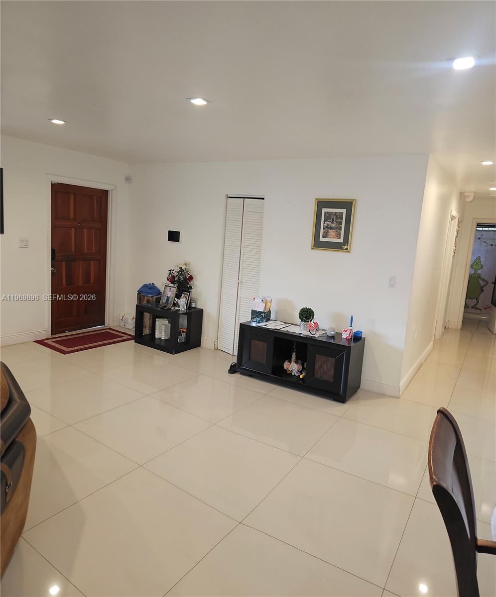 A bright entryway features white walls, tile flooring, a wooden front door, and two black consoles — 1760 NW 135th St, Miami FL 33167, MIAMI, FL