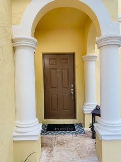 A brown front door is framed by two white columns under a yellow arched entryway — 4948 SW 136th Avenue, Miramar FL 33027, MIRAMAR, FL