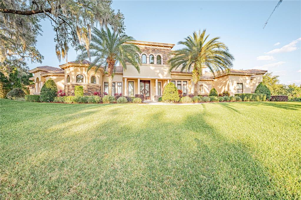 A large, two-story stucco home with a stone facade, arched windows, and two palm trees — 410 CANTERWOOD DRIVE, MULBERRY, FL