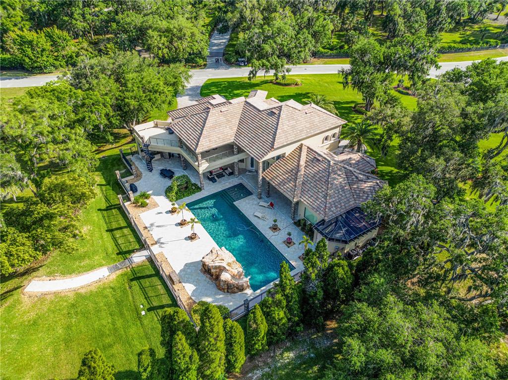 An aerial view shows a large house with a tiled roof, pool, and rock feature — 410 CANTERWOOD DRIVE, MULBERRY, FL