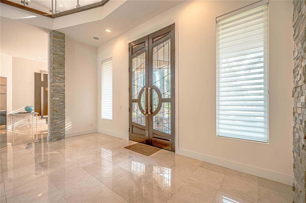 A bright entryway features polished tile floors, double glass-paneled doors, and stone-accented walls — 410 CANTERWOOD DRIVE, MULBERRY, FL