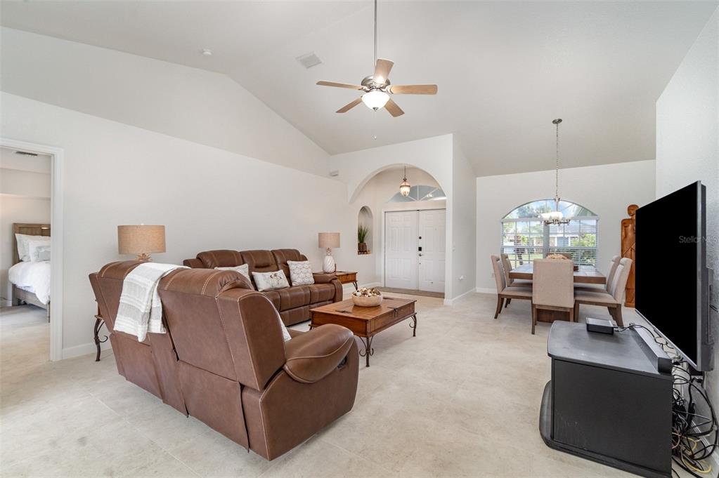 A living room with vaulted ceilings, tile flooring, brown leather furniture, and an adjacent dining area — 4186 YUCATAN CIRCLE, PORT CHARLOTTE, FL