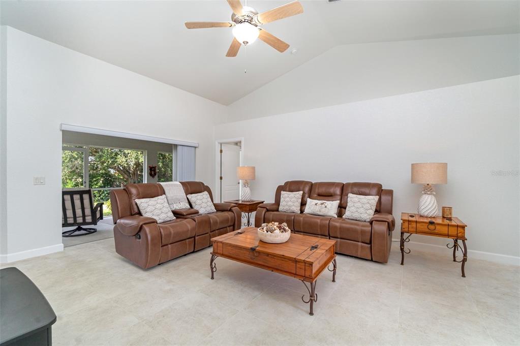 A living room features two brown leather sofas, a wooden coffee table, and a ceiling fan — 4186 YUCATAN CIRCLE, PORT CHARLOTTE, FL