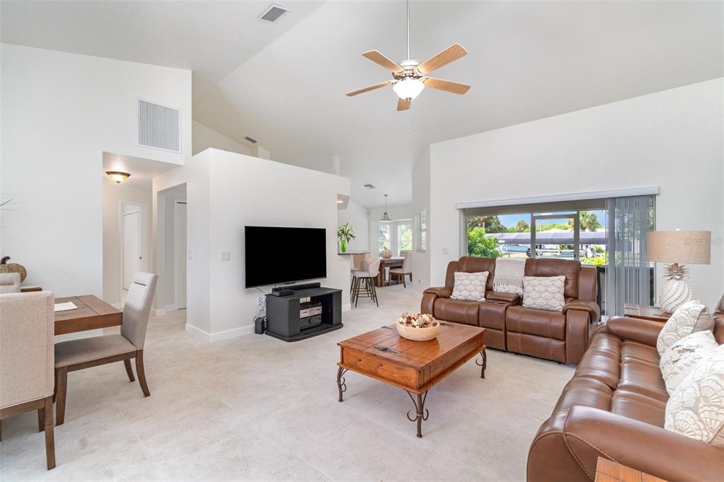 A living room with a vaulted ceiling, brown leather sofas, and a wooden coffee table — 4186 YUCATAN CIRCLE, PORT CHARLOTTE, FL