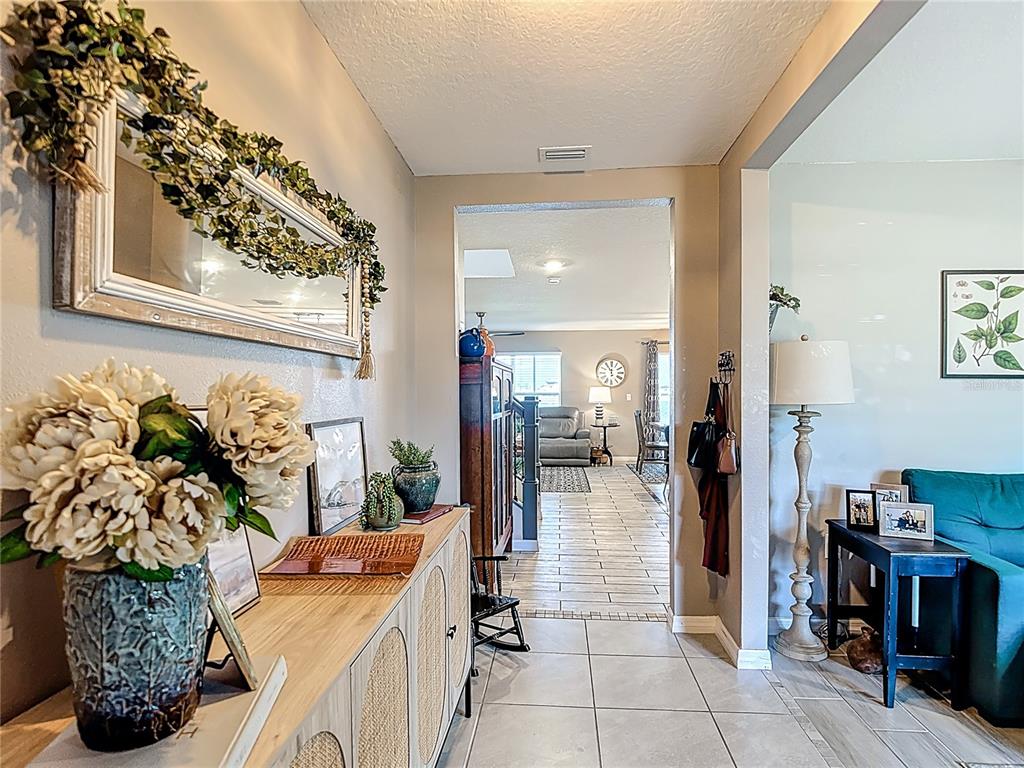 A view from a tiled entryway looking into a living room with light-colored walls — 38287 SONNET LANDING AVENUE, ZEPHYRHILLS, FL