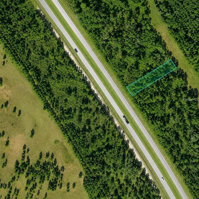 An aerial view shows a rectangular plot of land highlighted in blue beside a highway — US 27 HIGHWAY UNIT 517, FROSTPROOF, FL