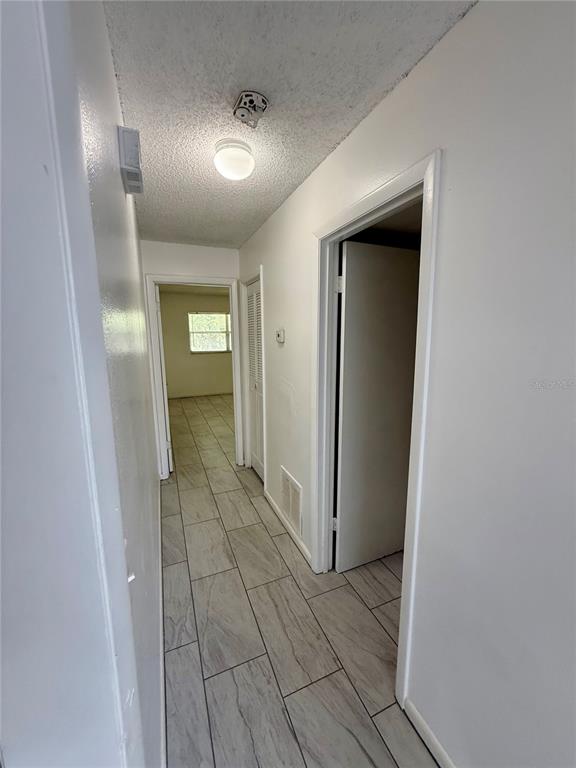 A hallway with light-colored tile flooring leads to a room with a window — 7047 BALBOA DRIVE UNIT 7047, ORLANDO, FL